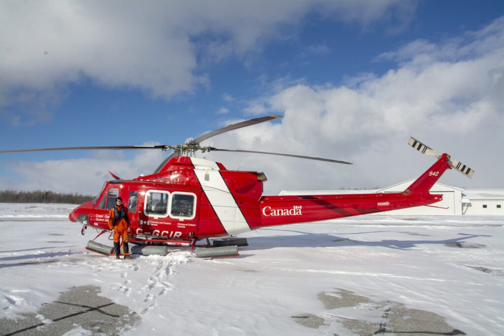 Warren standing in front of a red Coast Guard helicopter.
