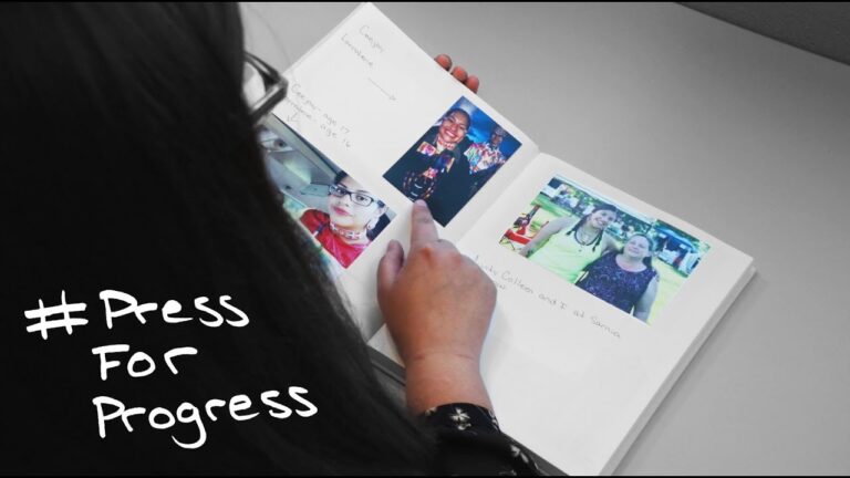 A woman pointing to a photo scrapbook, shot over her shoulder.