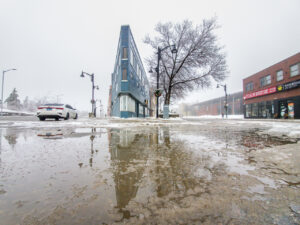 The flatiron building in Sudbury reflected in an icy puddle.