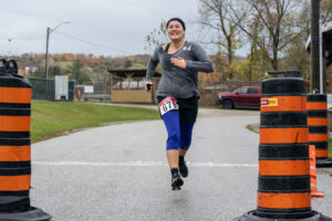 A woman runs straight toward the camera across a race finish line.