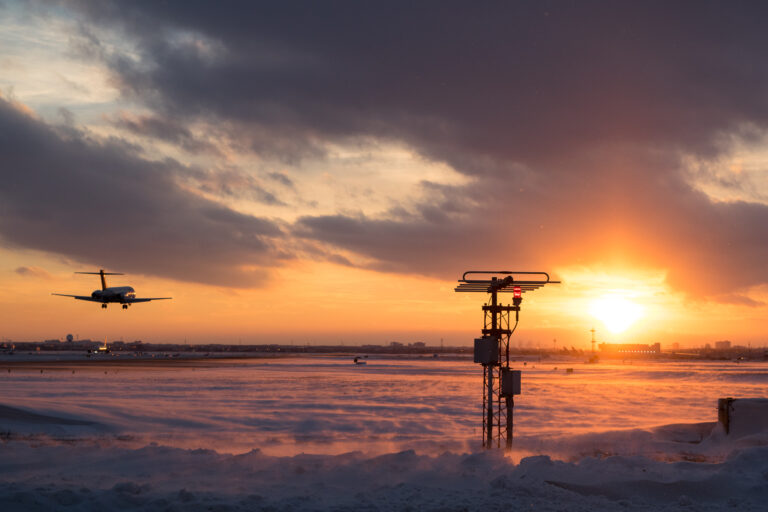 A silhouetted plane nears touchdown into a dazzling sunset at Toronto Pearson Airport.