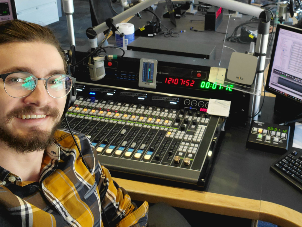 Selfie of me behind a radio mixing board.